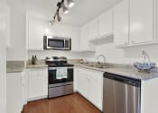 Thumbnail 20 of 26 - a kitchen with white cabinets and stainless steel appliances at Casa De Oro Apartments, California