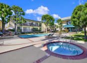 Thumbnail 2 of 36 - a jacuzzi and swimming pool in front of an apartment building at Copa Ladeene Apartments, Torrance California