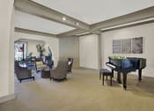Thumbnail 14 of 36 - a living room with a piano and a dining room with chairs at Copa Ladeene Apartments, Torrance California