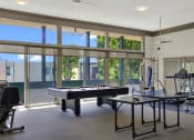 Thumbnail 12 of 36 - a game room with a pool table and a gym with windows at Copa Ladeene Apartments, Torrance, CA 90505