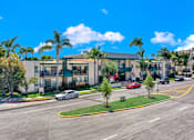 Thumbnail 7 of 36 - a building with palm trees and cars parked in front of it at Copa Ladeene Apartments, Torrance, 90505