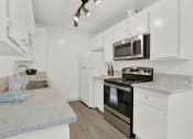Thumbnail 23 of 36 - a kitchen with white cabinets and stainless steel appliances at Copa Ladeene Apartments, California, 90505
