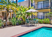 Thumbnail 4 of 26 - a swimming pool with a table and chairs under an umbrella at Copa Triana Apartments, California, 90505