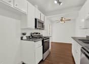 Thumbnail 19 of 26 - a kitchen with white cabinets and a stove and a microwave at Copa Triana Apartments, Torrance California