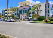 Thumbnail 6 of 18 - the front of a building with palm trees and cars parked outside  at Royal Towers Apartments, Redondo Beach, CA