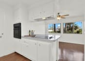Thumbnail 14 of 18 - a kitchen with white cabinets and a counter top and a black refrigerator  at Royal Towers Apartments, Redondo Beach, 90277