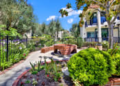 Thumbnail 11 of 55 - a patio with a fire pit and plants in a garden at Willow Tree Apartments, Torrance