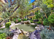 Thumbnail 9 of 55 - a pond in a garden with trees and rocks at Willow Tree Apartments, Torrance