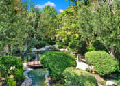 Thumbnail 8 of 55 - a bridge over a pond in a garden at Willow Tree Apartments, Torrance, CA, 90505