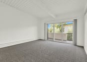 Thumbnail 33 of 55 - an empty living room with carpet and a sliding glass door at Willow Tree Apartments, Torrance
