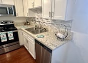 Thumbnail 12 of 26 - A kitchen with a stove, sink, and cabinets.