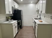 Thumbnail 41 of 55 - a kitchen with white cabinets and a black stove and refrigerator at Willow Tree Apartments, California, 90505