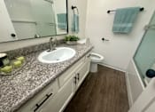 Thumbnail 55 of 55 - A bathroom with a granite countertop and white cabinets. at Willow Tree Apartments, California, 90505
