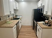 Thumbnail 45 of 55 - A kitchen with white cabinets and a black fridge at Willow Tree Apartments, California, 90505