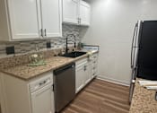 Thumbnail 43 of 55 - A kitchen with white cabinets and a granite countertop at Willow Tree Apartments, California, 90505