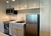 Thumbnail 35 of 36 - A kitchen with a stainless steel refrigerator and white cabinets.