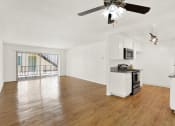 Thumbnail 25 of 36 - an empty living room with a kitchen and a ceiling fan at Casa Del Amo Apartments, Torrance