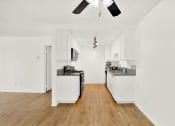 Thumbnail 22 of 36 - an empty kitchen with white walls and wood floors and a ceiling fan at Casa Del Amo Apartments, Torrance California