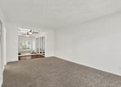 Thumbnail 16 of 19 - an empty living room with white walls and a ceiling fan at Olive Tree Apartments, Torrance