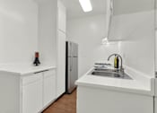 Thumbnail 18 of 19 - a kitchen with white cabinets and a sink and a refrigerator at Olive Tree Apartments, Torrance California