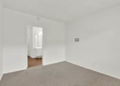 Thumbnail 19 of 19 - an empty living room with white walls and a carpet at Olive Tree Apartments, Torrance
