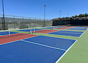 Thumbnail 56 of 56 - A tennis court with blue and green playing surface and white lines.