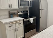 Thumbnail 24 of 54 - A kitchen with black appliances and white cabinets. at Camino de Oro Apartments, Torrance, CA, 90505