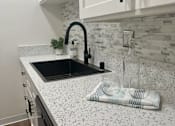 Thumbnail 23 of 54 - A kitchen with a black sink and a white speckled countertop. at Camino de Oro Apartments, Torrance, CA, 90505