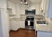 Thumbnail 11 of 26 - A kitchen with white cabinets and a black microwave above the stove.