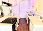 Thumbnail 18 of 18 - A kitchen with a black stove top oven and white cabinets at Royal Towers Apartments, Redondo Beach, CA, 90277