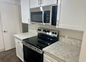 Thumbnail 15 of 26 - A kitchen with black appliances and white cabinets. at Copa Triana Apartments, Torrance
