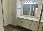 Thumbnail 16 of 26 - A bathroom with a sink, mirror, and cabinets. at Copa Triana Apartments, Torrance