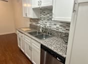 Thumbnail 17 of 26 - A kitchen with a granite countertop and white cabinets.  at Casa De Oro Apartments, Torrance, 90505