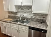 Thumbnail 15 of 26 - A kitchen with a granite countertop and white cabinets.  at Casa De Oro Apartments, Torrance, 90505