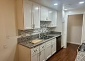 Thumbnail 16 of 26 - A kitchen with white cabinets and a granite countertop.  at Casa De Oro Apartments, Torrance, 90505