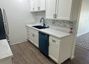 Thumbnail 22 of 54 - A kitchen with white cabinets and a blue dishwasher. at Camino de Oro Apartments, Torrance, CA, 90505