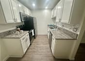 Thumbnail 54 of 55 - A kitchen with white cabinets and a granite countertop. at Willow Tree Apartments, California, 90505
