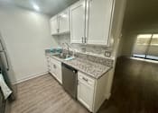Thumbnail 53 of 55 - A kitchen with white cabinets and a granite countertop. at Willow Tree Apartments, California, 90505