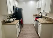Thumbnail 51 of 55 - A kitchen with black appliances and white cabinets at Willow Tree Apartments, California, 90505
