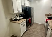 Thumbnail 52 of 55 - A kitchen with white cabinets and a black fridge at Willow Tree Apartments, California, 90505