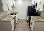 Thumbnail 50 of 54 - A kitchen with black appliances and white cabinets.