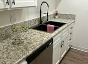 Thumbnail 49 of 54 - A kitchen with a granite countertop and a black dishwasher.