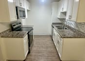 Thumbnail 26 of 26 - A kitchen with granite countertops and white cabinets.