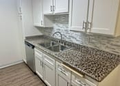 Thumbnail 25 of 26 - A kitchen with granite countertops and white cabinets.
