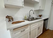Thumbnail 20 of 40 - A kitchen with white cabinets and wooden floors.