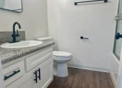 Thumbnail 31 of 36 - a bathroom with a toilet and a sink and a shower at Copa Ladeene Apartments, Torrance California