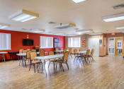 Thumbnail 6 of 10 - a multipurpose room with tables and chairs and a tv