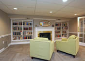 Thumbnail 13 of 25 - a library with two green chairs and a fireplace