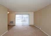 Thumbnail 6 of 25 - an empty living room with a large window and carpeting