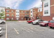 Thumbnail 5 of 14 - a parking lot with cars in front of a brick building